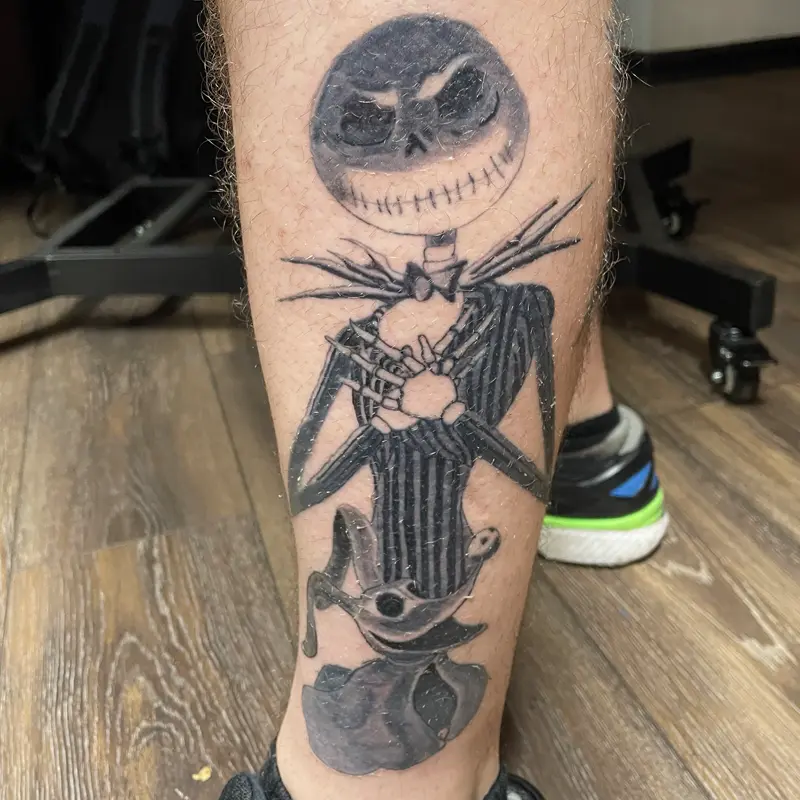 Black and gray tattoo of Jack Skellington with Zero the ghost dog on the back of the calf, by Andres at Killer Silver Tattoo