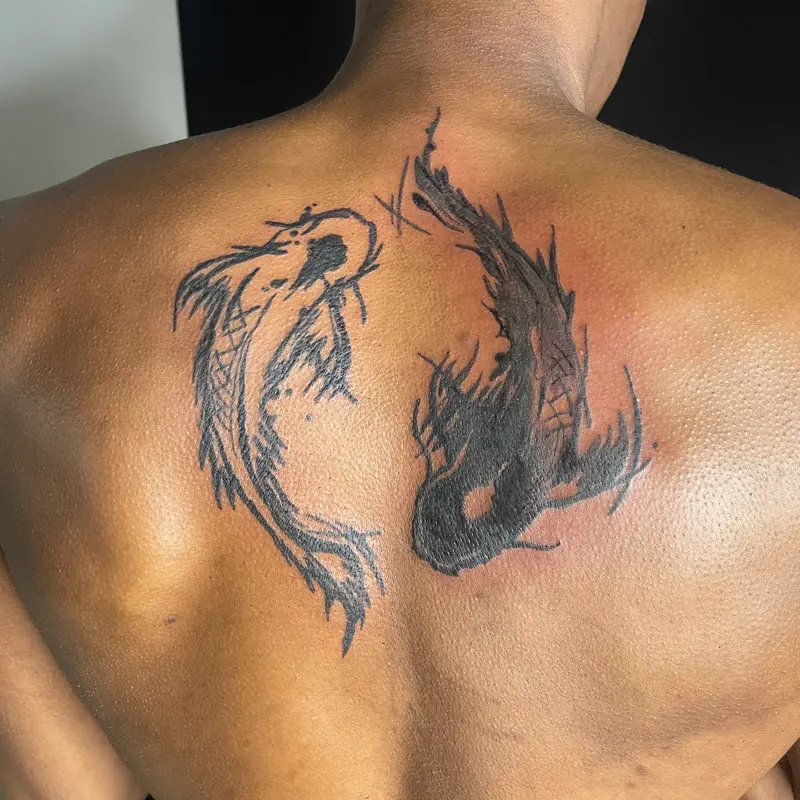 Blackwork yin-yang koi fish tattoo in sketchy brushstroke lines on the upper back, by Andres at Killer Silver Tattoo