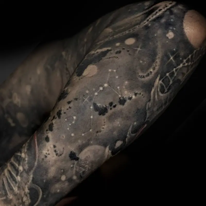 Black and gray realism forearm tattoo of a starfield with planets, DNA strands, water molecules and a hidden Scorpio constellation