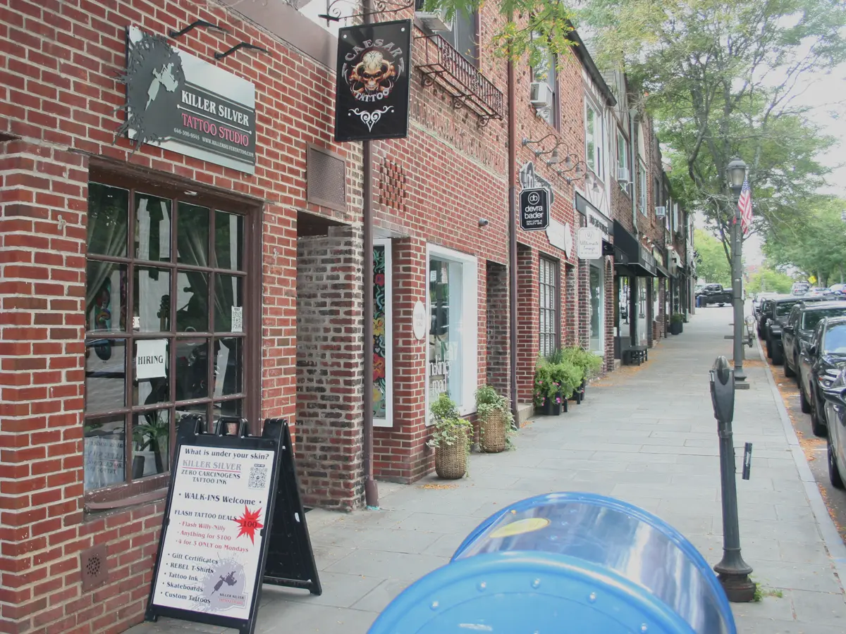 Killer Silver Tattoo storefront on the Scarsdale NY sidewalk, with Zero Carcinogens tattoo ink sandwich board sign