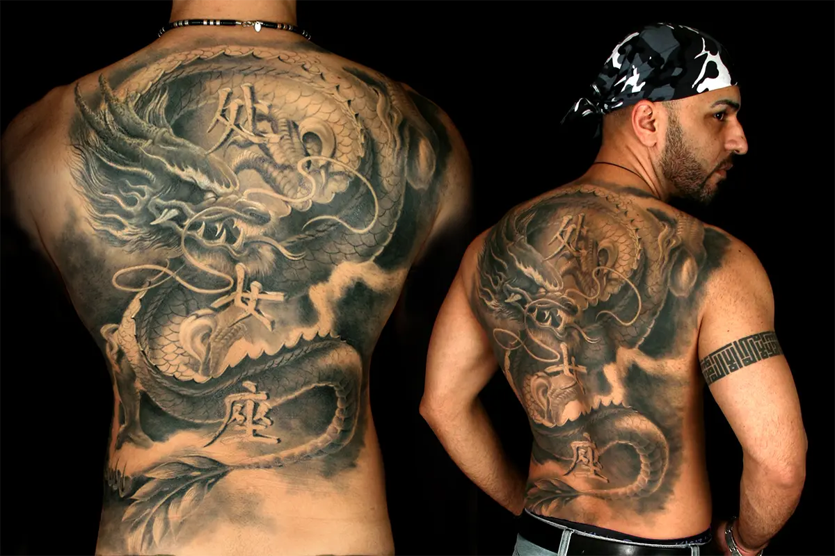 Black and gray dragon back piece with kanji by Caesar The Hun, shown straight on and over the client's shoulder