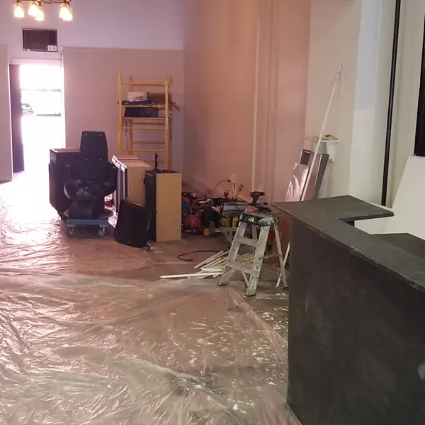 Renovation at 34 Garth Rd in Scarsdale, with a tattoo chair and cabinets waiting under plastic sheeting, 2021