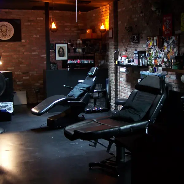 Two black tattoo chairs inside Killer Silver Tattoo Studio at 172 Avenue B, with exposed brick walls